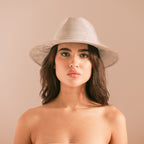 Woman wearing a light gray hat against a beige background
