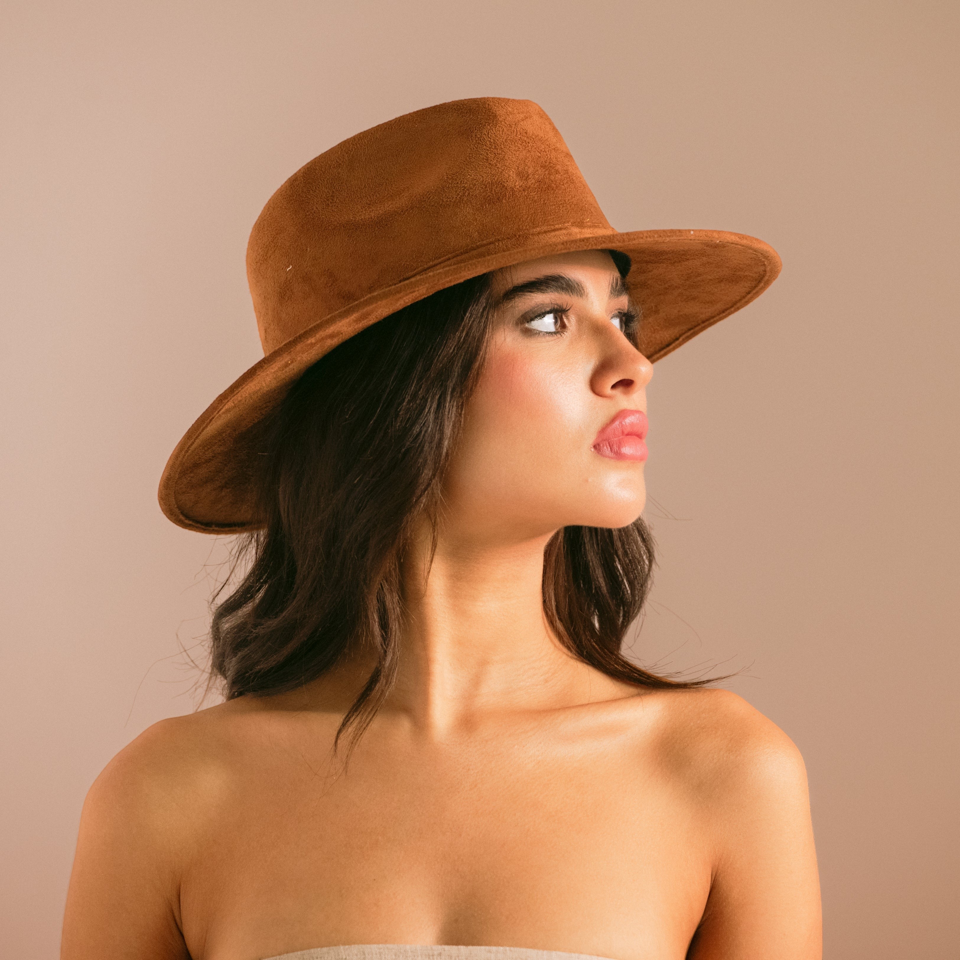 Woman wearing a brown hat against a beige background