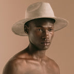 Man wearing a beige hat against a beige background