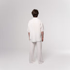 NESHOW white Bambula cotton camp shirt with short sleeves and raw hem, paired with matching wide-leg pants.