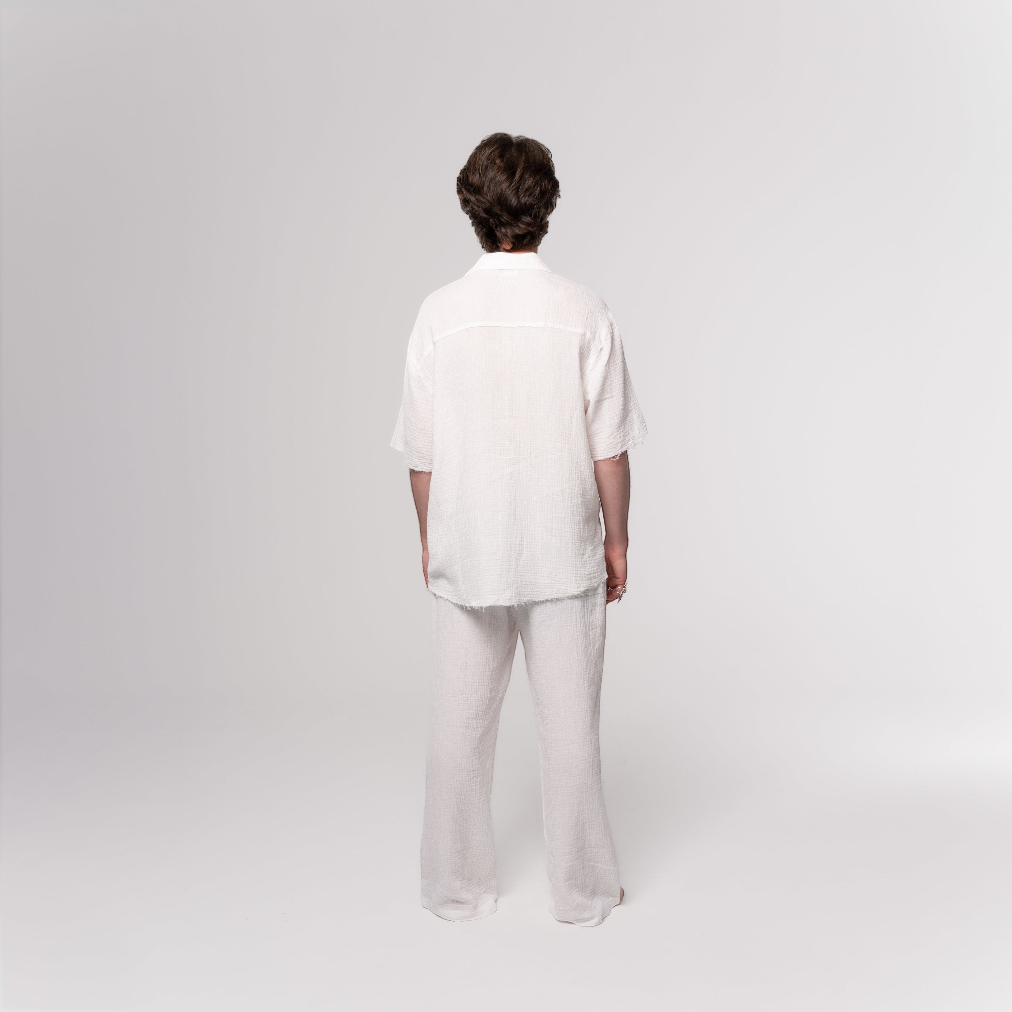NESHOW white Bambula cotton camp shirt with short sleeves and raw hem, paired with matching wide-leg pants.